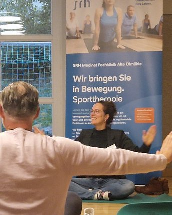 Bezugstherapeutin macht mit Rehabilitanden Yogaeinheit.
